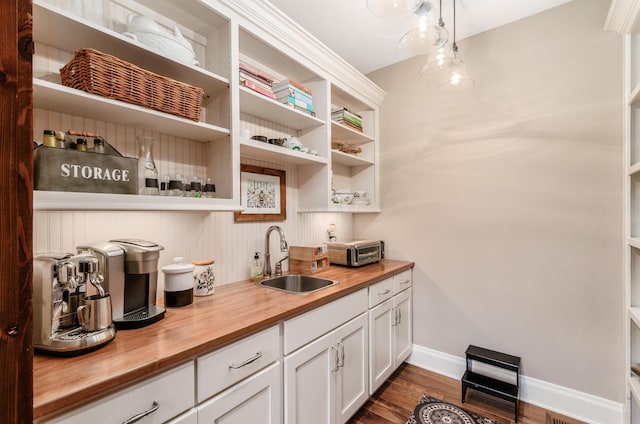 bar featuring pendant lighting, white cabinetry, sink, and wooden counters