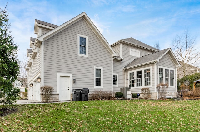 back of property featuring a yard, central AC unit, and a garage