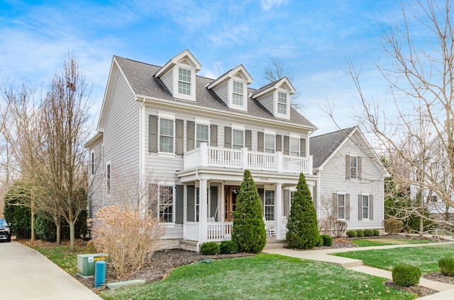 cape cod-style house featuring covered porch, a balcony, and a front yard