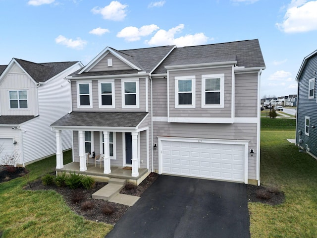 view of front of property with covered porch, a garage, and a front lawn