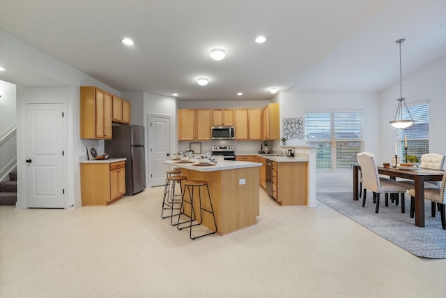 kitchen featuring a breakfast bar, light brown cabinets, hanging light fixtures, appliances with stainless steel finishes, and a kitchen island