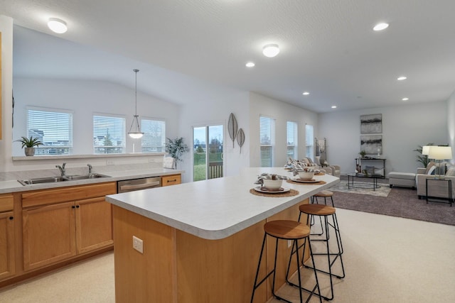 kitchen with a kitchen breakfast bar, stainless steel dishwasher, sink, decorative light fixtures, and a center island