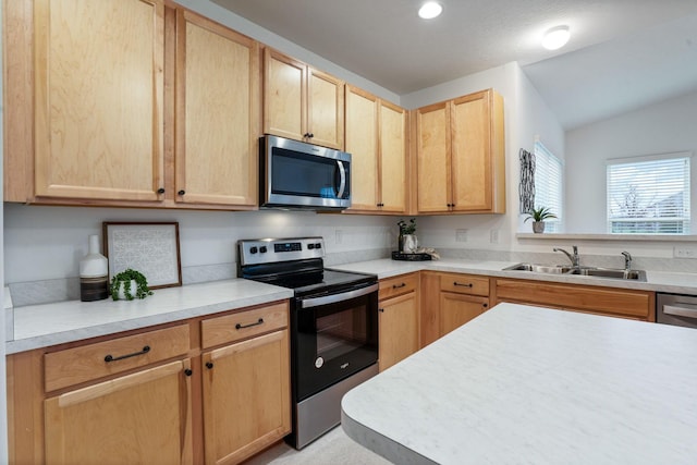 kitchen with light brown cabinets, sink, stainless steel appliances, and vaulted ceiling