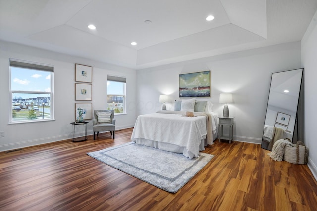 bedroom featuring a raised ceiling and dark hardwood / wood-style floors