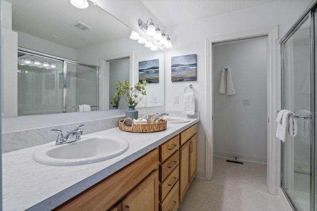 bathroom featuring a shower with door, vanity, and a textured ceiling