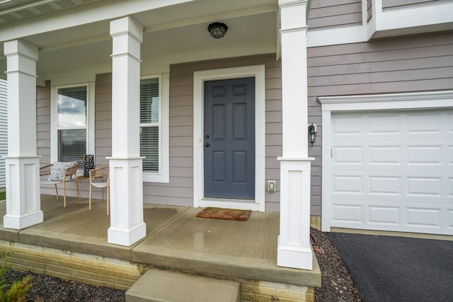 view of exterior entry featuring covered porch and a garage