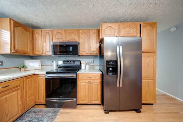 kitchen with light hardwood / wood-style flooring, stainless steel appliances, and a textured ceiling