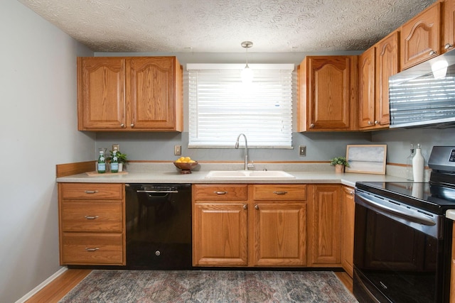 kitchen with hanging light fixtures, sink, black appliances, and a textured ceiling