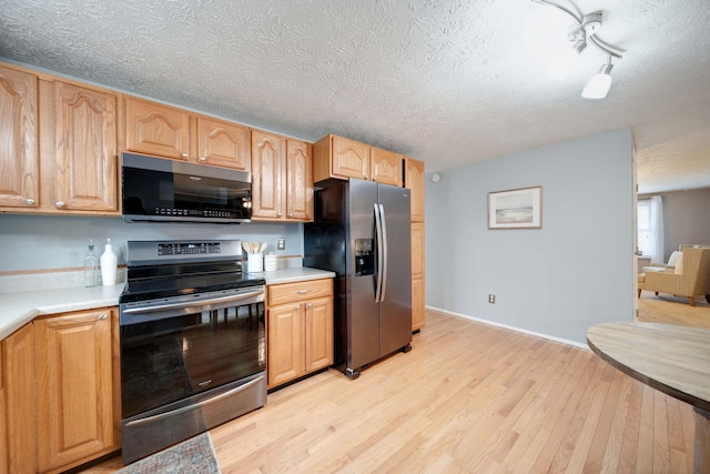 kitchen featuring a textured ceiling, light wood-type flooring, stainless steel appliances, and rail lighting