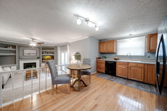 kitchen with stainless steel refrigerator, built in shelves, dishwasher, sink, and light hardwood / wood-style floors