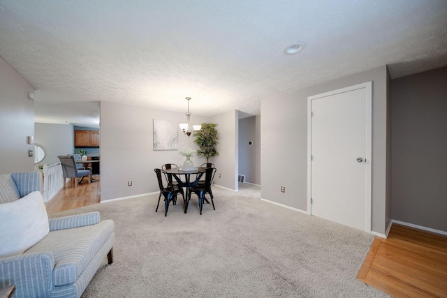 dining space featuring a textured ceiling, light carpet, and a chandelier