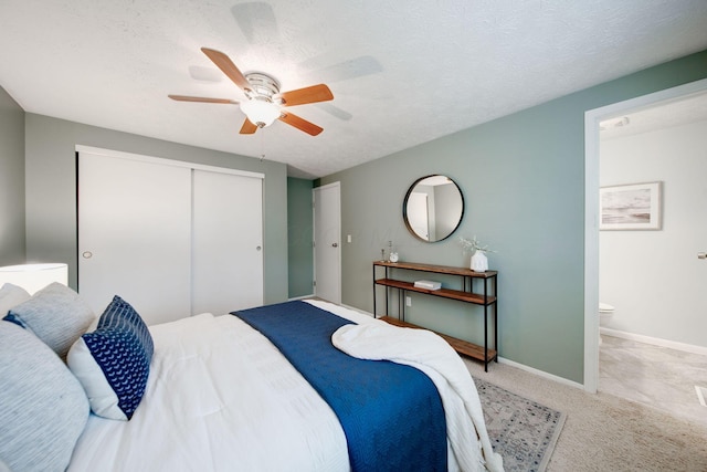 bedroom with light carpet, ceiling fan, a textured ceiling, connected bathroom, and a closet