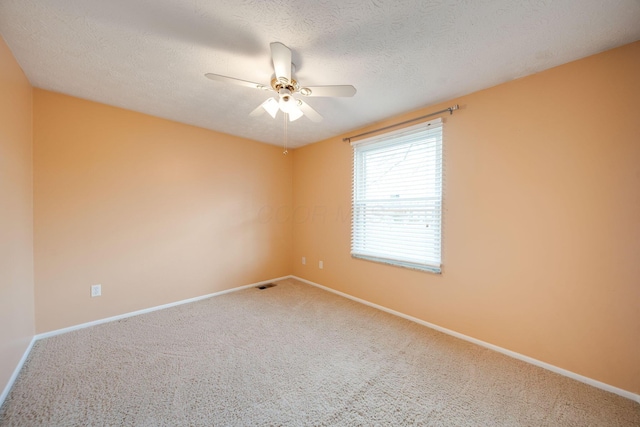 carpeted spare room featuring a textured ceiling and ceiling fan