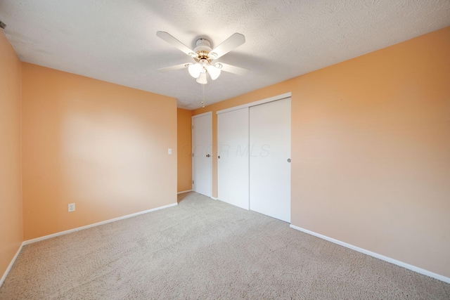 unfurnished bedroom with carpet, ceiling fan, a textured ceiling, and a closet