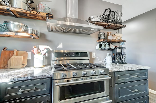 kitchen featuring island exhaust hood, wood-type flooring, light stone counters, and stainless steel range with gas stovetop