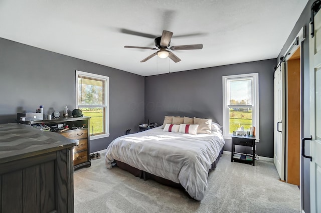 carpeted bedroom featuring a barn door and ceiling fan