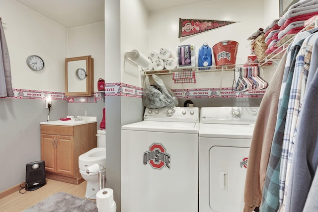 washroom featuring light wood-type flooring, laundry area, washing machine and dryer, and a sink