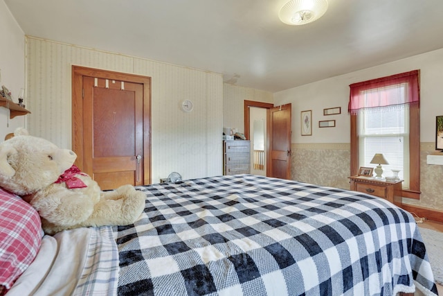 bedroom featuring wainscoting and wallpapered walls