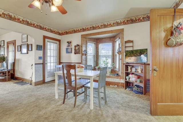 dining area with carpet floors, arched walkways, ceiling fan, and baseboards