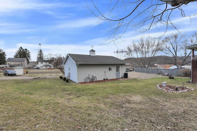 rear view of property with a chimney, a shingled roof, a lawn, fence, and an outdoor structure