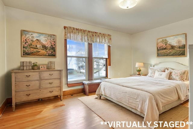 bedroom with light wood finished floors and baseboards