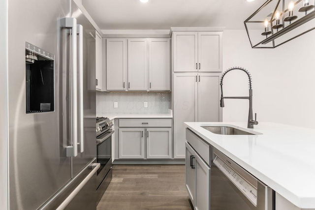 kitchen with dark hardwood / wood-style flooring, tasteful backsplash, stainless steel appliances, sink, and decorative light fixtures