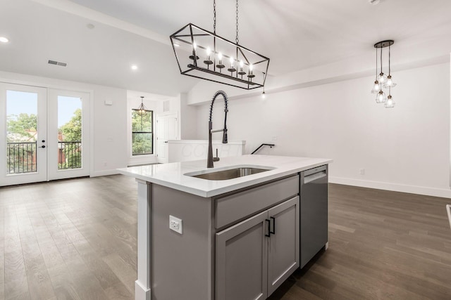 kitchen with a center island with sink, sink, stainless steel dishwasher, gray cabinets, and decorative light fixtures