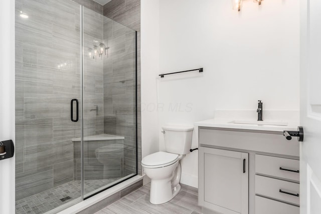 bathroom with vanity, toilet, and a shower with door