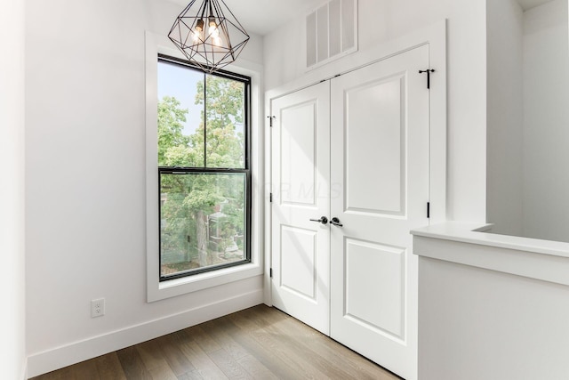 interior space featuring a wealth of natural light, an inviting chandelier, and light wood-type flooring