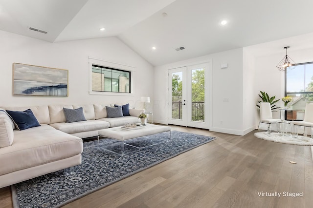 living room featuring french doors, wood-type flooring, vaulted ceiling, and an inviting chandelier