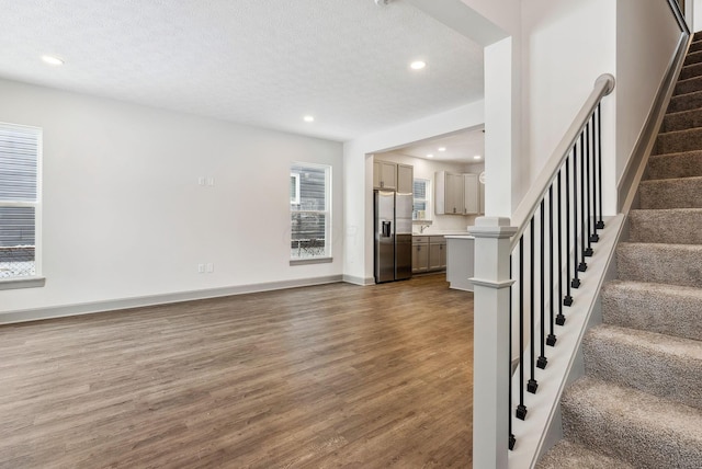 unfurnished living room with a textured ceiling and dark hardwood / wood-style floors