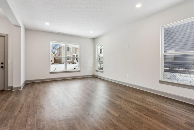 spare room featuring a wealth of natural light, dark hardwood / wood-style floors, and a textured ceiling