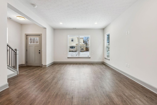 foyer entrance with dark hardwood / wood-style floors and a textured ceiling