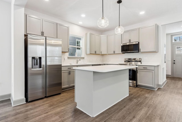 kitchen featuring gray cabinetry, a center island, dark wood-type flooring, hanging light fixtures, and stainless steel appliances