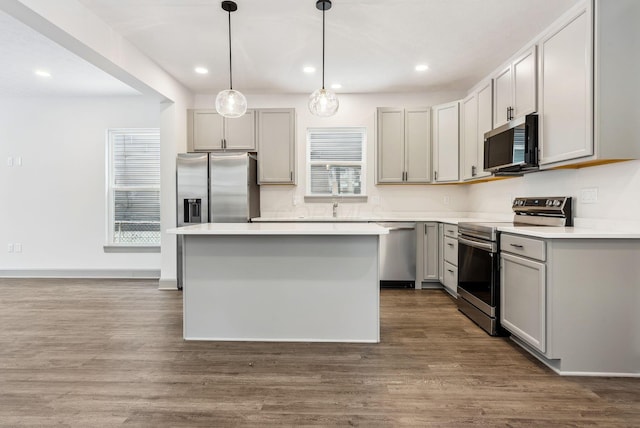 kitchen featuring gray cabinets, a center island, decorative light fixtures, and appliances with stainless steel finishes