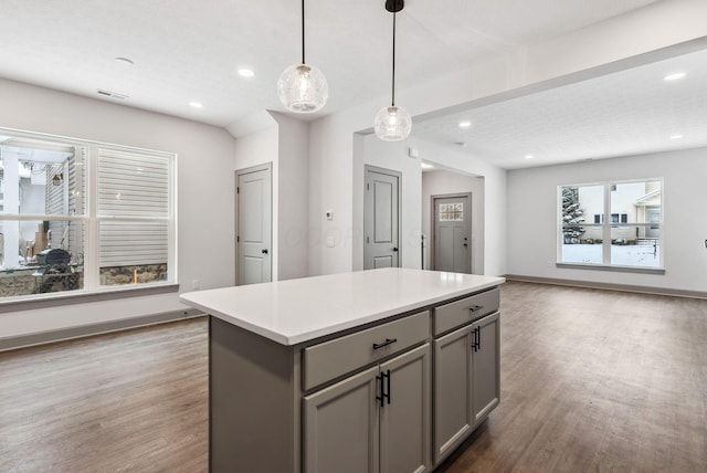 kitchen featuring gray cabinetry, decorative light fixtures, a kitchen island, and dark wood-type flooring