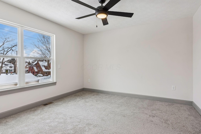 carpeted empty room featuring ceiling fan and a textured ceiling