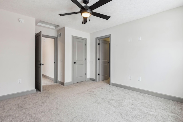 unfurnished bedroom with a textured ceiling, light colored carpet, and ceiling fan