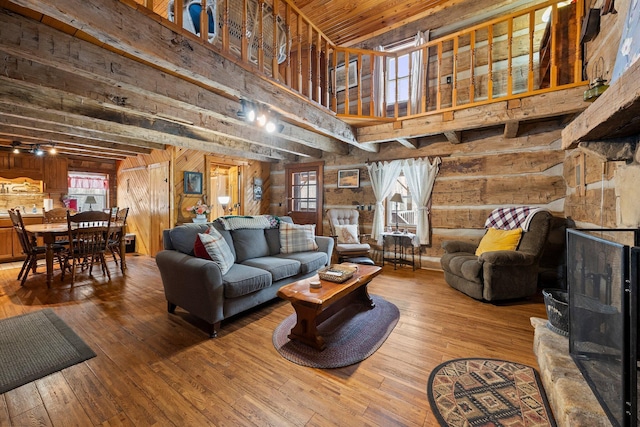 living room with a high ceiling, hardwood / wood-style floors, a healthy amount of sunlight, wood walls, and wooden ceiling