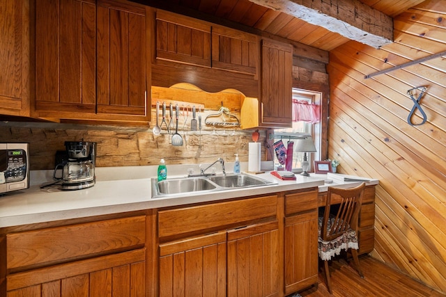 kitchen with sink, wooden walls, and hardwood / wood-style flooring