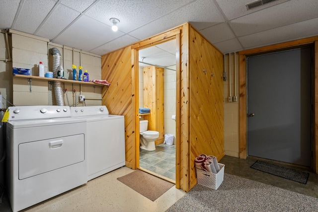 laundry area featuring separate washer and dryer and wood walls