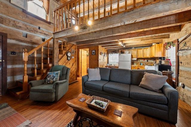 living room featuring a healthy amount of sunlight, hardwood / wood-style floors, wooden walls, and beamed ceiling