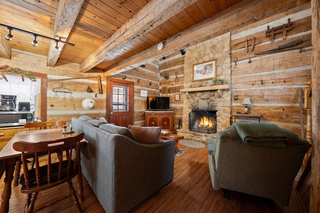 living room featuring track lighting, log walls, a stone fireplace, dark hardwood / wood-style floors, and beam ceiling