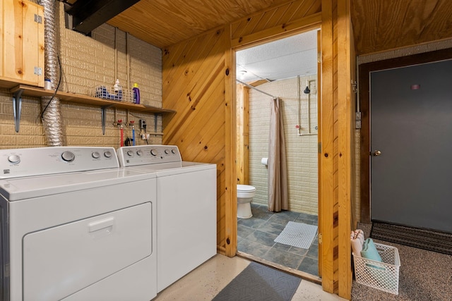 washroom with washing machine and dryer and wood walls