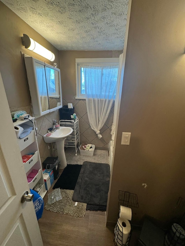 bathroom featuring a textured ceiling and tile walls