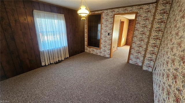 carpeted empty room with ornamental molding and wooden walls