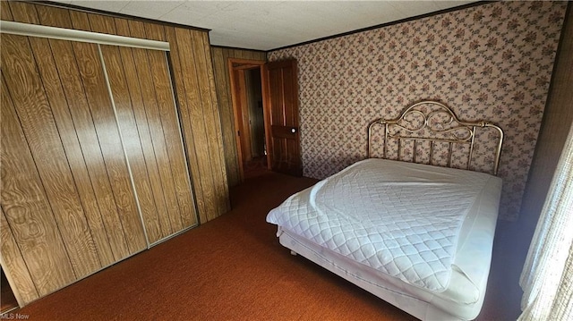 bedroom featuring crown molding, a closet, dark carpet, and wooden walls