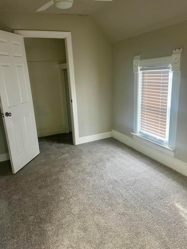 unfurnished bedroom with ceiling fan, a closet, carpet, and vaulted ceiling