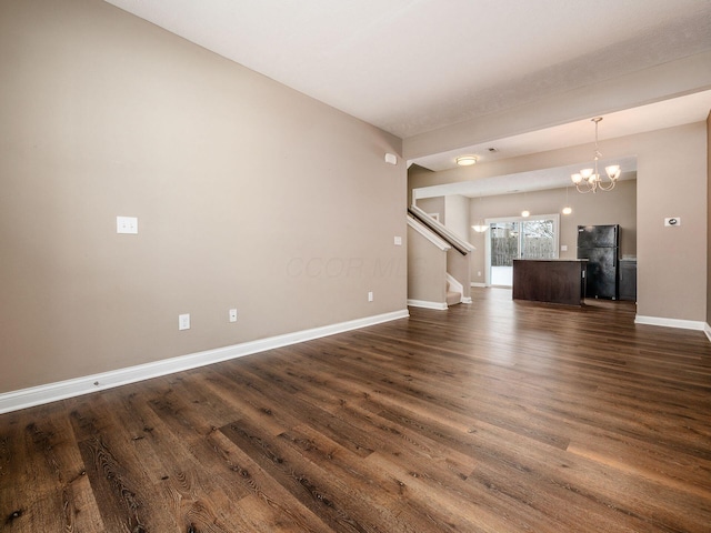 unfurnished living room with dark hardwood / wood-style flooring and an inviting chandelier