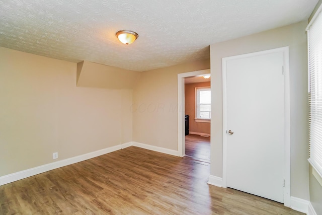 unfurnished room featuring light wood-type flooring and a textured ceiling